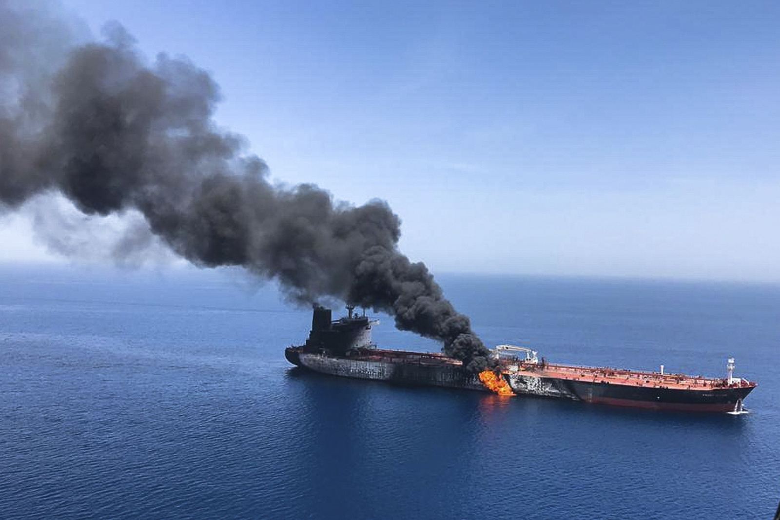 Un petrolier arde în larg; un nor gros de fum negru se ridică deasupra punții, iar flăcările ies din bordaj.